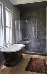 In a newly installed bathroom, slate tile encases the shower and a soaking tub takes in the view of a cluster of 100-year-old Norway Spruces.