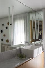 A Carrara marble counter lines the vanity, and a mirror stretches from wall to wall.