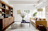 Zachary designed a new cabinet in walnut to anchor the room. The wood tones are a warm counterpoint to the butter-yellow sofa. The coffee table belonged to the owners.