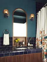 “It’s kind of a moody, dark bathroom,” says Tang. An inset walnut mirror custom-designed by Tang mingles with zellige tiles by Mosaic House. The vanity sconces are theater wall lights from Germany by Cosack, sourced via 1stdibs.