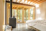 A pair of double doors leads to the large screened porch. At the ceiling, rafters underscore the skylight, casting shadows that mark the passage of the sun.