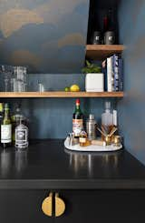 Around the corner behind the stairs, they tucked a bar nook and pantry, which is where the refrigerator is located. The wallpaper is by MakeLike, the concrete tile is Zia Tile in Midnight, the counter is Ikea butcher block that’s stained ebony, and the pulls are by Lo&amp;co.