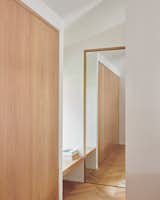 The entrance to the walk-in closet is marked by another bench floating across the window, and a mirror inset in white oak.