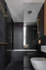 Large-format tiles, a glass-enclosed tub and shower combo, and elegant gold fixtures create a luxurious bath retreat.