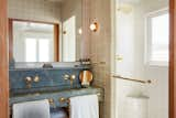 A monolithic, imported stone vanity in the bathroom is accented by brass fixtures and hand-cut and crafted tile.