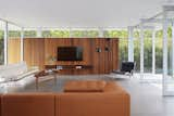 The Serge Mouille floor lamp is paired with the Fabricius & Kastholm Grasshopper chair in the living room. The custom walnut cabinet is mounted on red cedar siding, which provides a dramatic backdrop for the Eames sofa and a Finn Juhl coffee table of solid walnut.