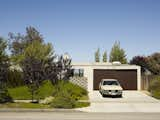 At a home designed by Escher GuneWardena Architecture in Los Angeles, California, the two-door garage has minimally-detailed doors in a darker color that slide horizontally, instead of rolling up or hinging inward.