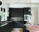 The kitchen features hacked IKEA cabinets—Brit and Daniel built custom fronts and side panels out of Valchromat, a recycled engineered wood. The cabinets are topped with black steel, which extends up the wall as backsplash. “We wanted to find an inexpensive way of doing a really terrific kitchen,” says Daniel. “The metal, which is a cold-rolled sheet of blackened steel, is a unique material that will develop a patina over time, but will also be super durable—and again, very cost effective.”