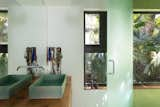 The master bath with cedar countertops overlooks views of a lush fan palm. The custom vessel sink was crafted by the owner.