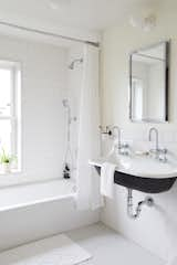 The kid's bathroom on the second floor is lined with white penny tile and white square tiles in a running bond pattern. The wallpaper is from Juju papers.