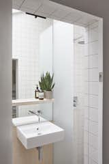 A peek inside the bathroom. This space is lined with matte white tiles and pale gray grout.

