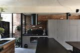 The open-plan living room, dining area and kitchen on the ground floor open up to the rear garden through folding glass doors. Concrete flooring helps improve thermal mass, while a minimalist palette of timber, stone and Equitone cement cladding used for a portion of the cabinet fronts help achieve a sleek and handsome look.