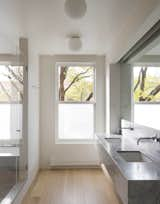 Oak flooring extends from the master bedroom into the bathroom, complementing the duo of marble sinks.