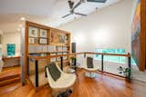 Cable railings extend across the open loft area, while open shelving houses colorful art.