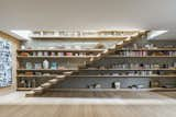 The floating oak staircase in the first-floor family room leads to the rooftop garden, which features a lounge area, grill, and small bar room with a restroom. Bespoke oak shelving behind the stair offers a display area for books and other objects. 