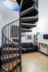 A spiral stair at the center of the living space leads downstairs to the lower "basement" level. The small spiral stair was the only solution for code-compliant vertical circulation in a house with such a small footprint. The alternative would have involved building a "saddlebag" onto the side of the house to create a traditional stair run, which would have exceeded the budget. 