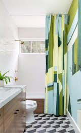 The colorful Porter Teleo wallpaper and custom, commissioned shower curtain in the kid's bathroom is offset by a funky white and charcoal tiled floor.