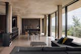 The open-space interior is divided by furniture and clusters of columns. Here, the kitchen flows into the dining and living room areas, heated by a wood-burning fireplace.