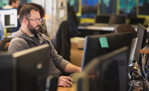 Image of a worker sitting at his computer, concentrating on the screen.