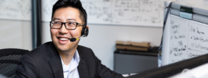 On office worker wearing a headset turns his head to react to a coworker.