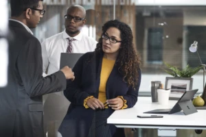 Three colleagues standing on an office in discussion.