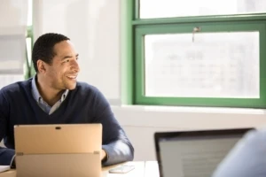 Small business male with laptop achieving in modern workplace.