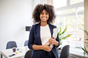 Young female professional at an office holding a laptop.