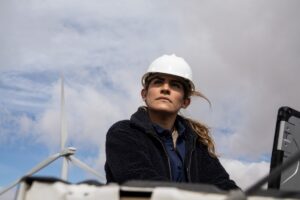 Field engineer using a laptop on truck tailgate to review data after inspection of turbines on a wind farm.