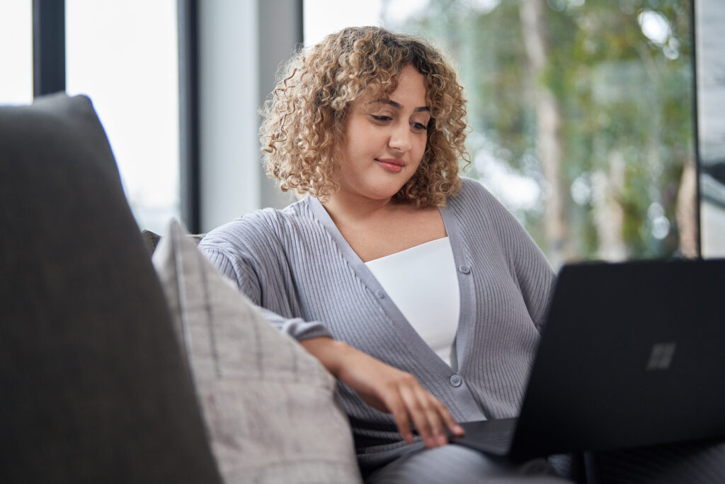 A person sitting down and looking at an open laptop screen.