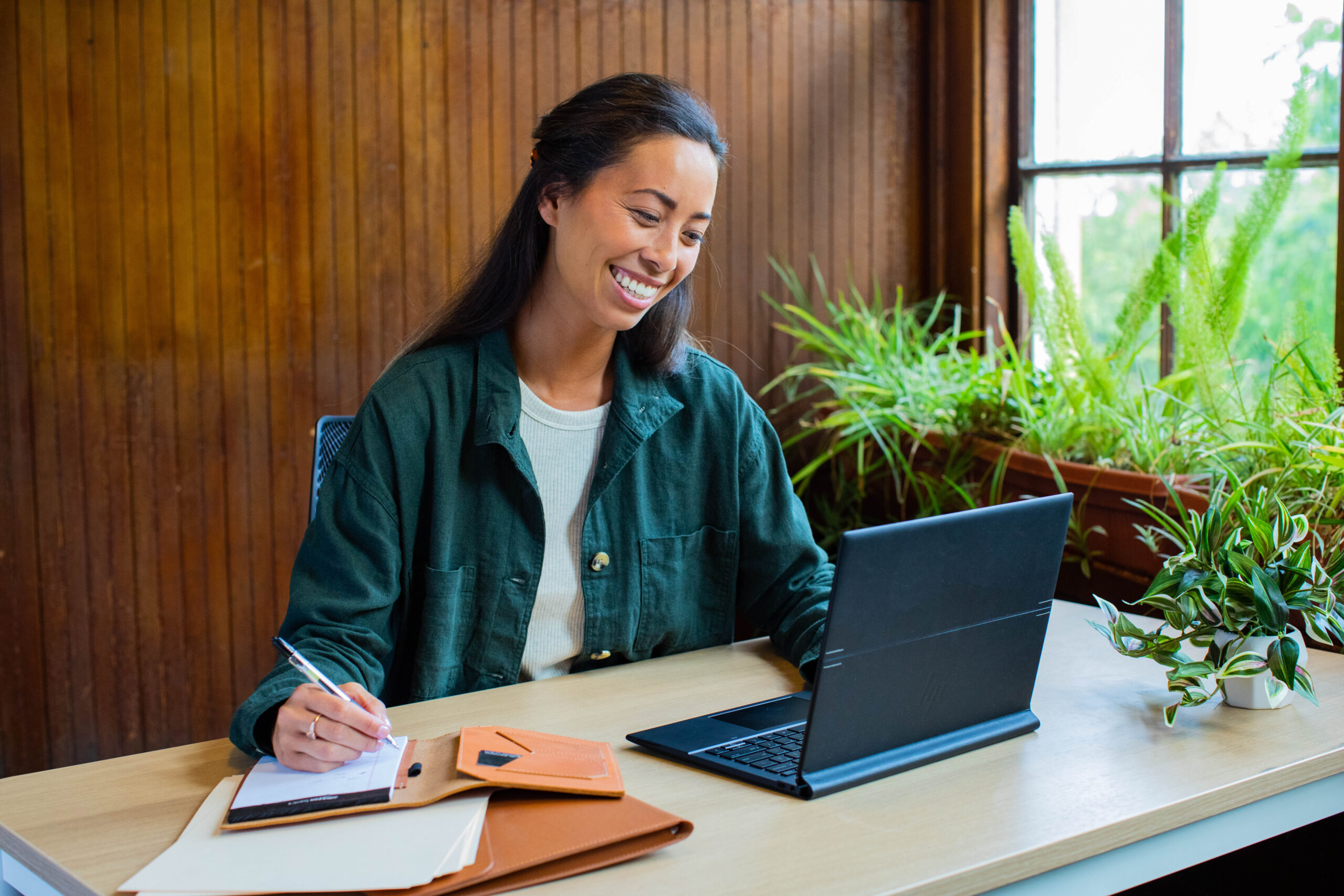 A person seated at a desk, actively working on a laptop.