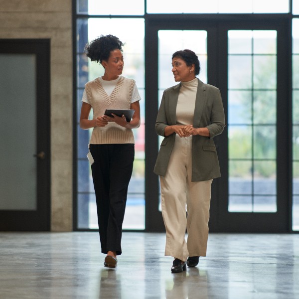 Two education leaders talking together while walking down a school hallway.