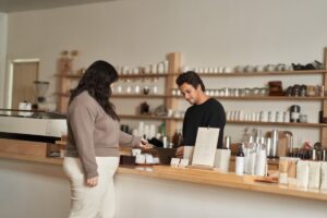 Customer using a mobile device to make a secure coffee shop purchase.