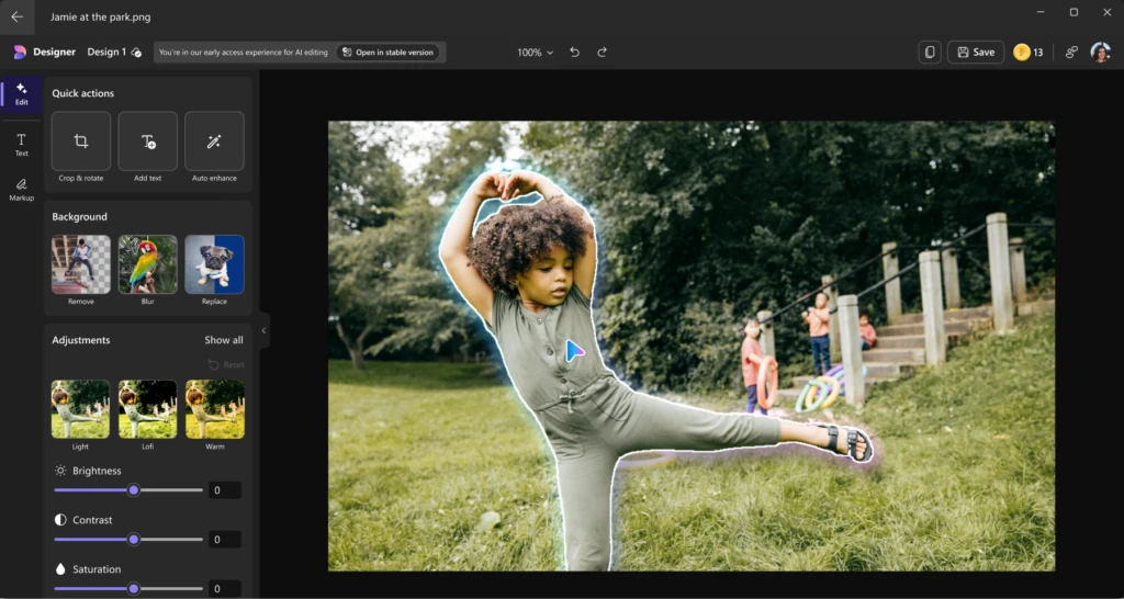 A young child with curly black hair and beige green shirt dancing in a park is being edited using Designer in Windows Photos.