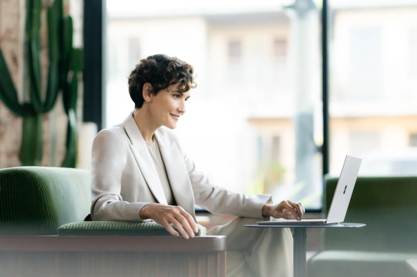 Decorative, a person sitting on lobby chair working on a Surface Laptop 6. 