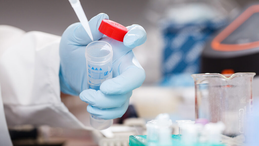 Cambridge lab - drug discovery | photo of a gloved hand holding a test tube