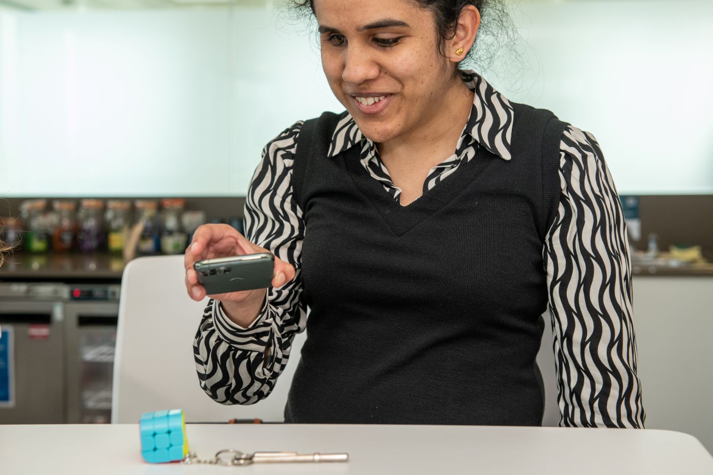 Find My Things | woman holding her mobile phone over keys on a desk