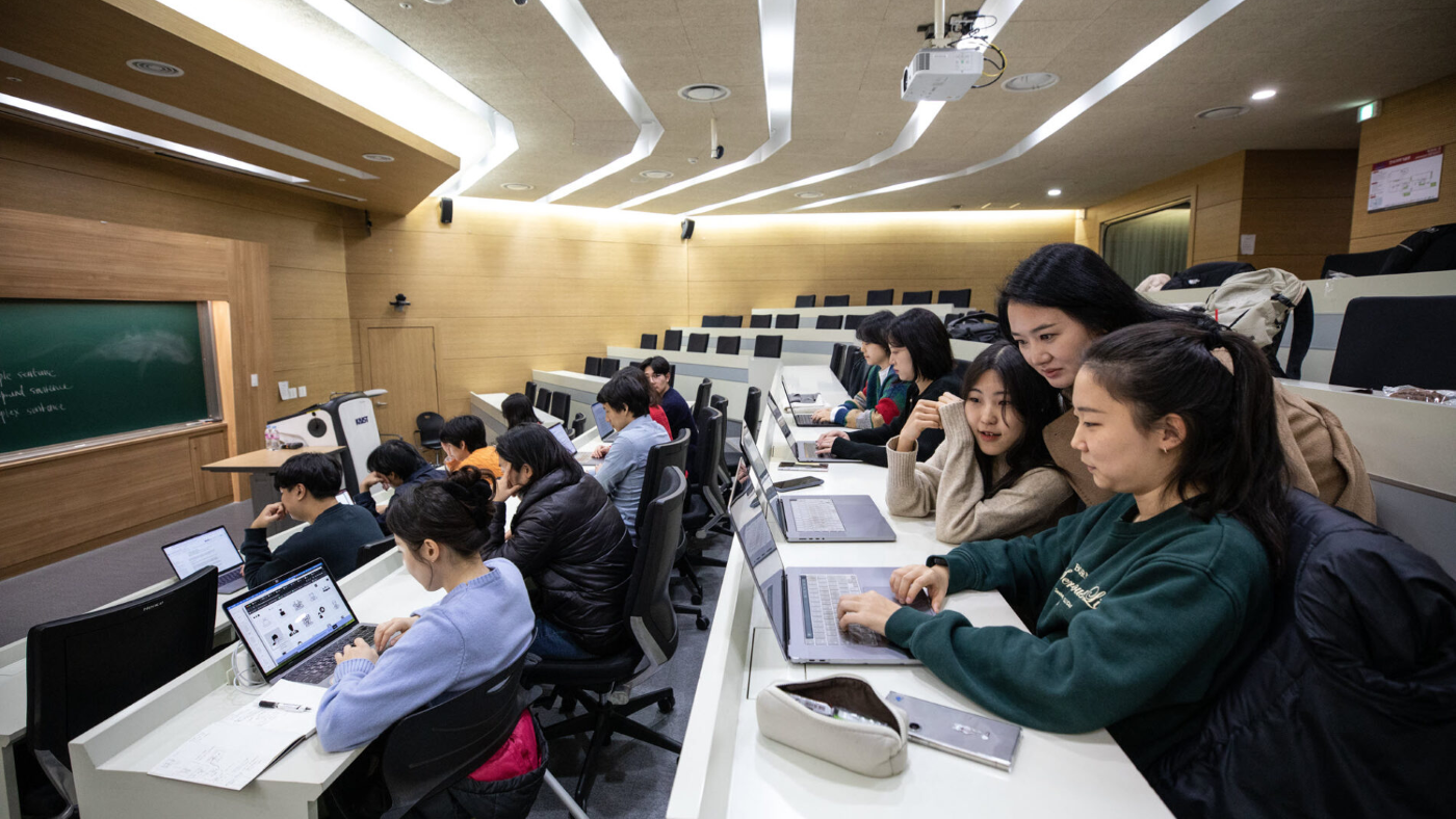 Students working at computer tables in a classroom