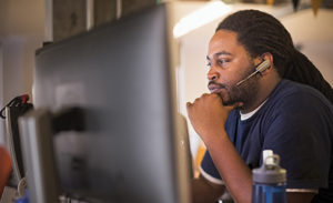 Tech worker in front a PC wearing headphones.