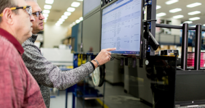 An image of two tech workers looking at a PC display in a data center.