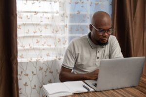 A young man works on his laptop from home.