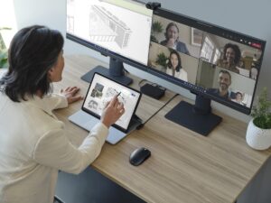 Adult female is collaborating on a Microsoft Teams video call presented on the right monitor, while Revit is in use on the left.