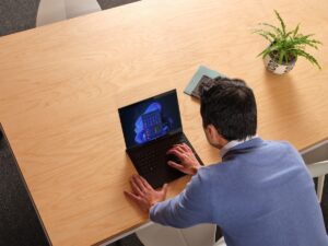 Business person calling up the Windows 11 Start Menu on laptop device.