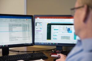 A man wearing glasses sorts through emails using Microsoft Outlook.