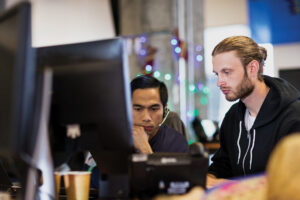 Two male engineers sitting in front of a computer screen.