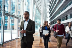 Photo of business professionals in foyer walking, chatting, holding deivces