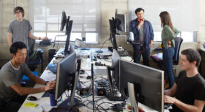 a group of people sitting at a table using a laptop computer