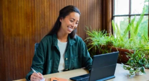 a woman sitting at a table using a laptop computer