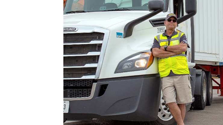 Photo of J.B. Hunt driver standing next to a white semi truck