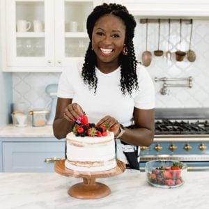 Zainab headshot in a modern white kitchen with cake.