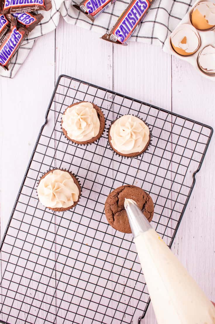 Piping the frosting onto the cupcakes.